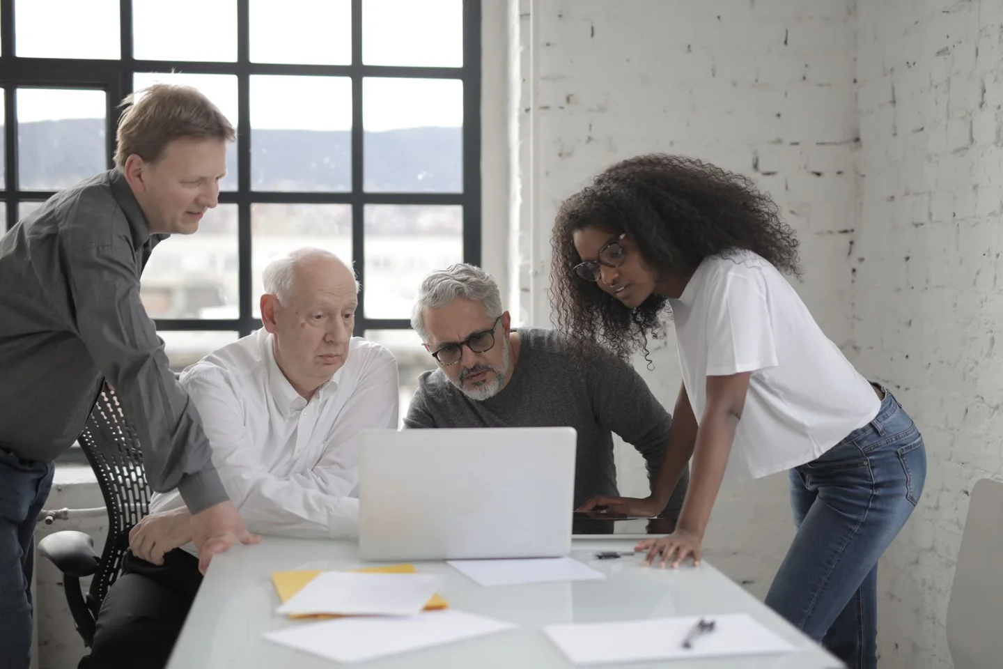 Colleagues reviewing work together around a laptop at a shared table.